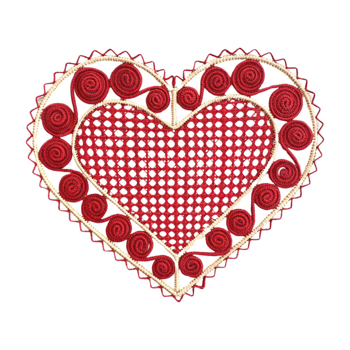 A woven placemat featuring a large red heart with intricate spiral designs, bordered by a red trim.